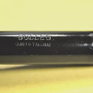 Puede incluir: Una pluma estilogr&aacute;fica negra con acabado brillante que presenta el texto grabado COLLEG y KAWECO-FABRIKAT en el cuerpo. La pluma tiene un cuerpo cil&iacute;ndrico con una secci&oacute;n estriada cerca de la tapa, mostrando letras met&aacute;licas claras.