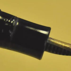 Puede incluir: Una pluma estilogr&aacute;fica negra con un plum&iacute;n de color oro met&aacute;lico. La pluma presenta un cuerpo cil&iacute;ndrico con una secci&oacute;n roscada cerca de la empu&ntilde;adura, que conduce al plum&iacute;n expuesto. El dise&ntilde;o es sencillo y funcional, mostrando la punta.