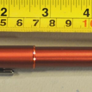 May include: A metallic rust-colored pen with a silver clip, positioned below a yellow measuring tape that shows the pen is approximately 5.5 inches in length. The pen features a smooth, cylindrical body with a thin orange ring at the center.