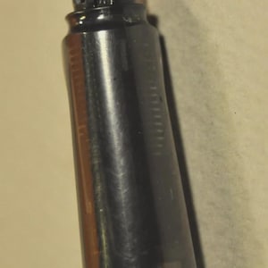 K&ouml;nnte beinhalten: Ein F&uuml;llfederhalter mit einem unteren Schaft aus silberfarbenem Metall und einem Griffst&uuml;ck aus durchscheinendem Dunkelgrau. Die Feder ist dunkel gef&auml;rbt und spitz zulaufend. Der interne Tintenleiter ist durch das halbtransparente Material sichtbar.