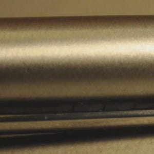 Może przedstawiać: Zbliżenie srebrnego długopisu ze szczotkowanym metalowym wykończeniem. Pi&oacute;ro posiada prostokątny klips z wygrawerowaną nazwą marki "LAMY". Korpus pi&oacute;ra jest cylindryczny i ma gładką, metaliczną fakturę.