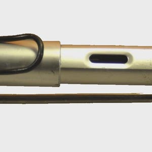 K&ouml;nnte beinhalten: Ein silberfarbener Lamy-F&uuml;llfederhalter mit matter Oberfl&auml;che, ausgestattet mit einem schwarzen Drahtclip an der Kappe und einem rechteckigen Sichtfenster f&uuml;r die Tinte am Schaft. Der Stift liegt waagerecht auf einem kleinen, dunklen Metallst&auml;nder.