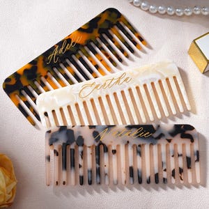 Może przedstawiać: Zestaw trzech ceramicznych kubków z nakrapianym, matowym wykończeniem. Kubki są w odcieniach kremowym, jasnoszarym i ciemnoszarym. Każdy kubek ma prosty, minimalistyczny design, idealny do kawy lub herbaty.