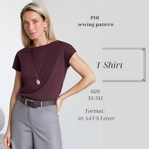 Può includere: Una donna indossa una maglietta bordeaux e pantaloni grigi. L'immagine include il testo "PDF sewing pattern" e "T-Shirt", con taglie da XS a 3XL. I formati sono A0, A4 e US Letter.