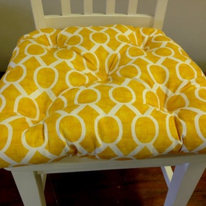 May include: A yellow and white patterned chair cushion with a tufted design.