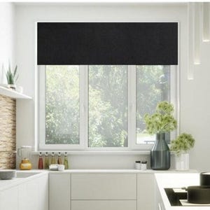 May include: Black blackout window shade installed in a kitchen with white cabinets and a stainless steel stove.