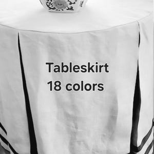 May include: White table skirt with black trim. The skirt has two black bands around the bottom. The text "Tableskirt 18 colors" is printed on the skirt.