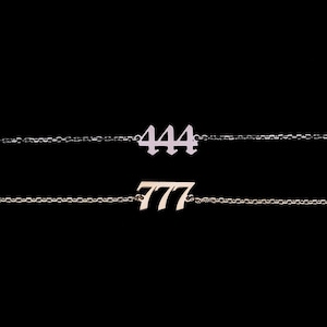 May include: Two delicate gold chain bracelets with the numbers 444 and 777 hanging from them.