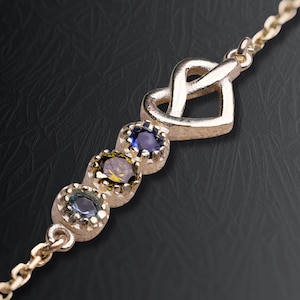 以下が含まれることがあります： ゴールドトーンのブレスレット。ハート型のチャームと、青と黄色の色合いの3つのオーバルカットの宝石が特徴です。 宝石はベゼルセッティングで、ブレスレットは繊細なチェーンが付いています。