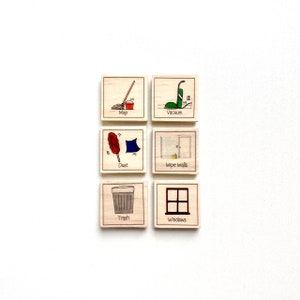May include: Six wooden blocks with illustrations of household chores. The blocks are labeled "Dust", "Mop", "Trash", "Vacuum", "Wipe Walls", and "Windows".