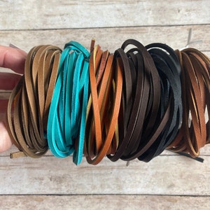 May include: A bundle of leather cords in various colors, including brown, turquoise, and black. The cords are arranged in a circular pattern, with the ends of the cords overlapping.