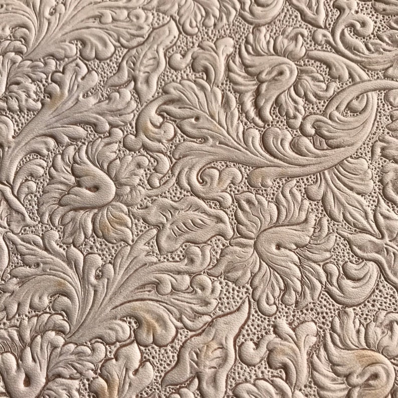 May include: A close-up of a white embossed leather with a floral pattern.