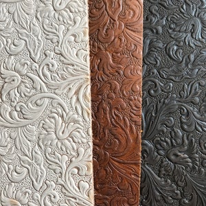 May include: Three strips of embossed leather in white, brown, and black. The leather has a floral pattern.