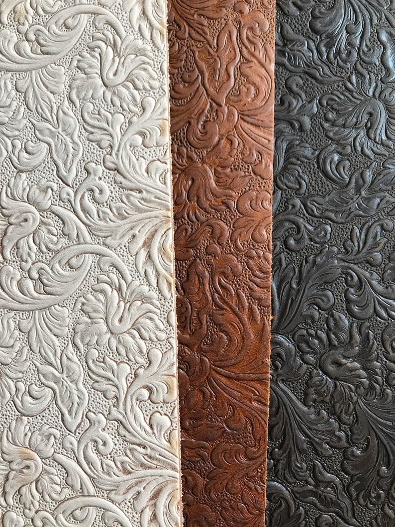 May include: Three strips of embossed leather in white, brown, and black. The leather has a floral pattern.