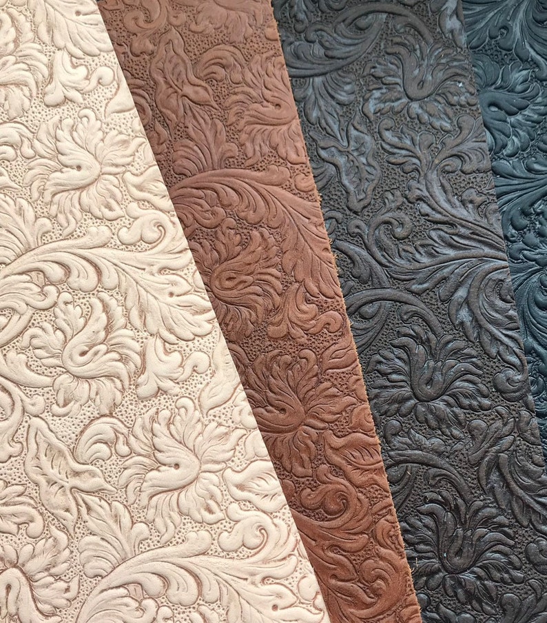 May include: Four samples of embossed leather fabric in different colors: off-white, brown, dark brown, and black. The fabric has a floral pattern.