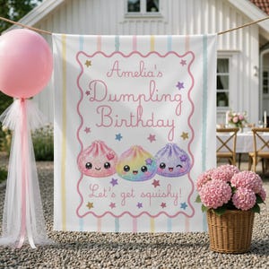 May include: A rectangular fabric banner featuring the text Amelia's Dumpling Birthday and Let's get squishy! The design includes three cartoon dumplings with faces, surrounded by colourful stars, enclosed in a pink scalloped border.