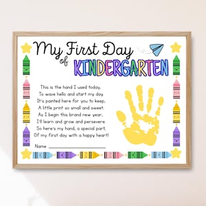 May include: A framed print with the text "My First Day of Kindergarten." The print features a yellow handprint, colorful crayons, and a paper airplane illustration. The text includes a poem about the first day of school.