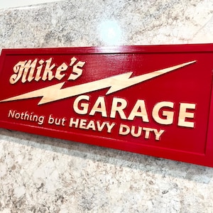 May include: Red wooden sign with a lightning bolt and the text "Mike's Garage Nothing but HEAVY DUTY".