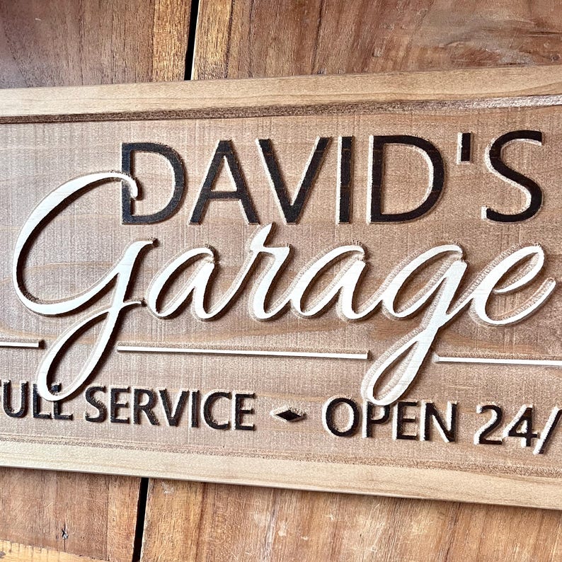 May include: A wooden sign with the text "David's Garage" in black lettering and "Full Service - Open 24/" in black lettering.