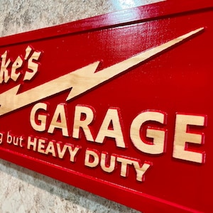 May include: Red wooden sign with a white lightning bolt and the text "Mike's Garage - Nothing but Heavy Duty".
