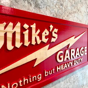 May include: Red wooden sign with a white lightning bolt and the text "Mike's Garage Nothing but Heavy Duty".