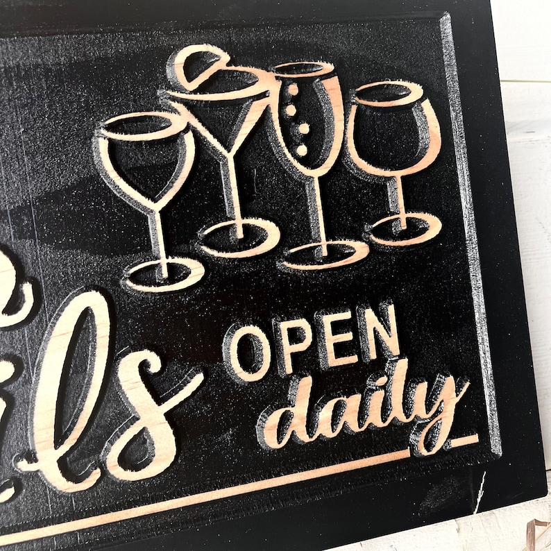 May include: Black wooden sign with the text "Open daily" and a graphic of five wine glasses. The sign has a rustic, distressed look.