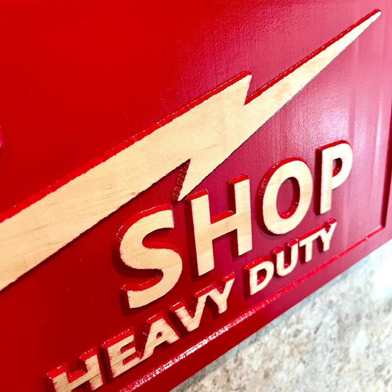 May include: Red wooden sign with a yellow lightning bolt and the words "SHOP HEAVY DUTY" in white lettering.