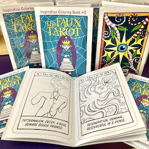 May include: A set of coloring books featuring illustrations of tarot cards with a whimsical, cartoon-like style. The books are titled "The Faux Tarot" and are labeled "Inspiration Coloring Book #3".
