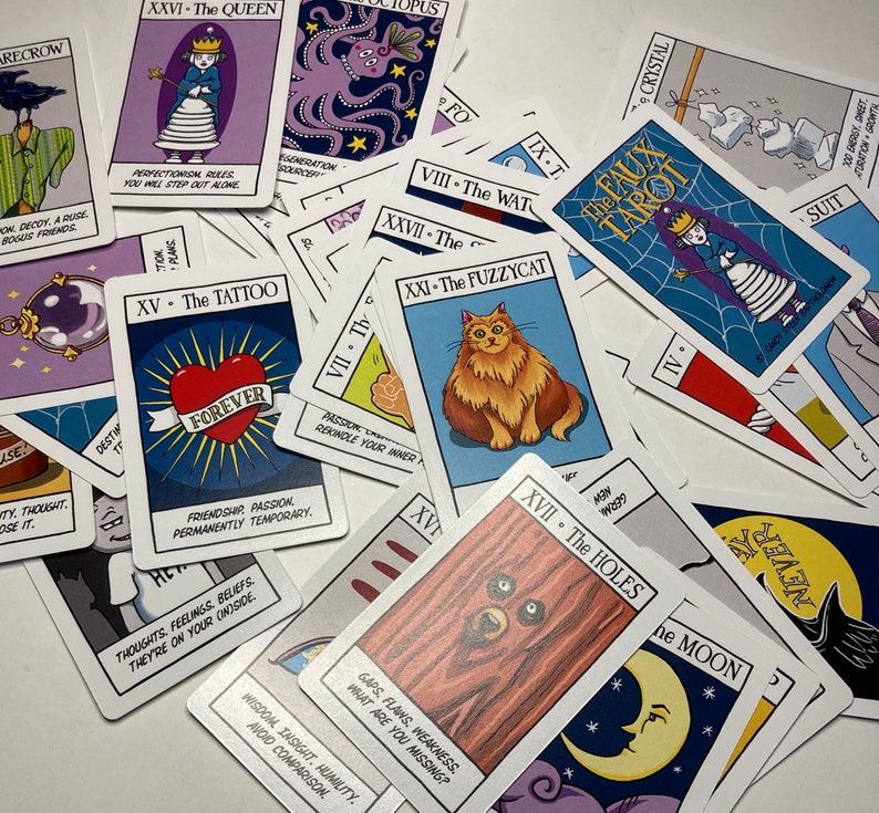 May include: A close-up of a deck of tarot cards with colorful illustrations and text. The cards are spread out on a white surface. The cards feature a variety of themes, including animals, nature, and abstract concepts. The text on the cards includes the names of the cards and their corresponding numbers.