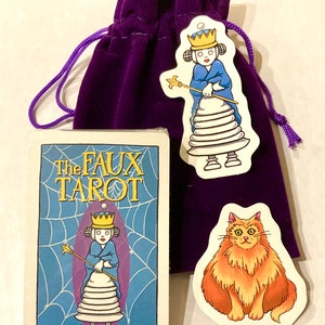 May include: A purple velvet bag with a drawstring closure contains a deck of cards called "The Faux Tarot" by Sandy Steen Bartholomew. The cards feature a cartoon illustration of a queen with a crown and a scepter. Two stickers are also included, one with a cartoon cat and the other with a cartoon queen.