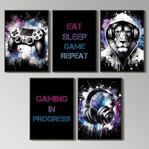 May include: Set of four black framed prints with watercolor backgrounds. The prints feature a video game controller, a lion wearing headphones, a pair of headphones, and the text "Gaming in Progress" and "Eat Sleep Game Repeat".