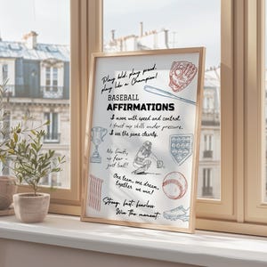 Pode incluir: Uma impressão emoldurada com afirmações de beisebol em tinta preta e azul. A impressão inclui ilustrações de equipamentos de beisebol e frases como "Play like a Champion" e "One team, one dream, together we win!" A moldura é de cor castanho claro.