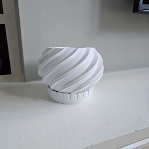 以下が含まれることがあります： 螺旋模様の白いセラミック製のプランター。プランターは滑らかでマットな仕上がりで、わずかに丸みを帯びた底になっています