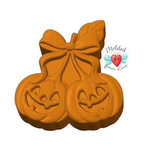 May include: Orange pumpkin-shaped decoration with two smiling jack-o'-lantern faces, a bow, and a leaf. The text "Molded from Love" is in the upper right corner. This Halloween-themed item is perfect for seasonal decor.