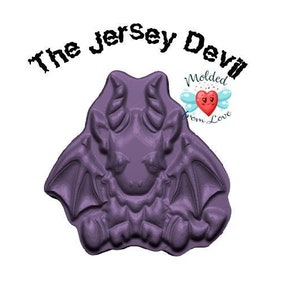 May include: A purple, molded figure of the Jersey Devil with horns, wings, and a detailed face. The text "The Jersey Devil" is above the figure in a jagged font. The figure is on a white background.