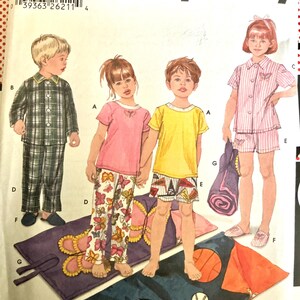 May include: A Simplicity sewing pattern envelope for children's pyjamas and sleeping bags. The illustration shows four children wearing various pyjama styles, including plaid sets, butterfly-print trousers, and striped shorts, alongside rolled sleeping bags.