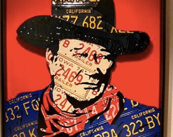 May include: A framed artwork featuring a portrait of a person wearing a cowboy hat made of license plates. The hat is made of license plates from different states, including California, Iowa, and New York. The background is a solid red color.