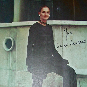 May include: A black and white photo of a woman wearing a black outfit with a black choker necklace. The photo is from a Vogue Paris Original pattern, designed by Yves Saint Laurent. The pattern number is 2296.