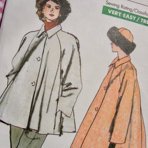 May include: A sewing pattern envelope featuring illustrations of two coats. One is a light gray, knee-length coat with a collar and buttons. The other is an orange, patterned, knee-length coat with a collar, buttons, and black gloves.