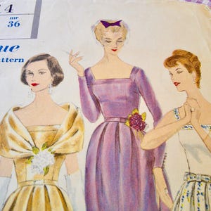 May include: Vintage Vogue printed pattern featuring illustrations of three women in elegant dresses. The pattern includes sizing information and the price. The dresses are in shades of gold, lavender, and white, with floral accents.