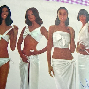 May include: Four women modeling white swimsuits and sarongs. The swimsuits are all white and have a simple design. The sarongs are also white and are tied around the waist.