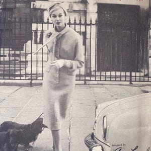 May include: A vintage Vogue Paris Original printed pattern envelope featuring a black and white photograph of a person in a tailored suit, hat, and gloves, accompanied by two dogs. The text reads Vogue Paris Original, printed pattern, and designed by Guy Laroche.
