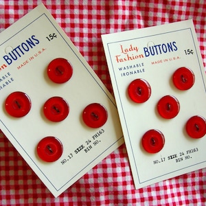 May include: Two cards with red buttons on them. The cards are white with black text that reads "Lady Fashion Buttons, Washable, Ironable, Made in U.S.A., 15¢, No. 17 Size 24 FH163, Bin No."