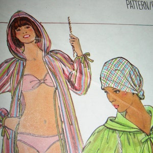 May include: Two fashion illustrations of women. The woman on the left is wearing a striped dressing gown with a pink bikini top and matching bottoms. The woman on the right is wearing a green dressing gown with a plaid headscarf.
