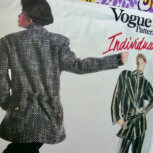 May include: A black and white tweed jacket with a long, fitted silhouette. The jacket has a collar and a button closure. The image is from a Vogue Patterns magazine, with the text "Vogue Patterns Individualist" printed on the page.