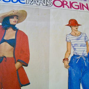 May include: A vintage fashion illustration from Vogue Paris Original. It depicts two figures: one in a red outfit with blue trim and a straw hat, the other in a striped top, blue trousers, and a red hat. The image is a pattern design.