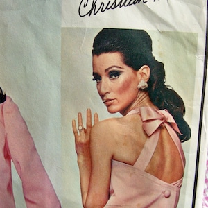 May include: A vintage sewing pattern for a pink sleeveless dress with a bow detail at the back. The pattern is by Christian Dior and has the number 1668 printed on it.