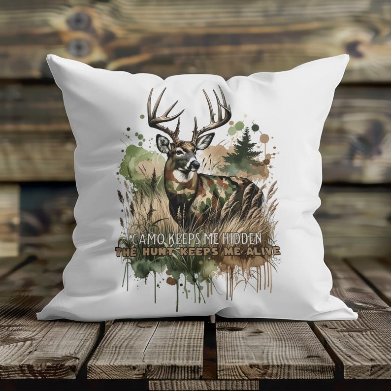 May include: White throw pillow with a watercolour design of a deer in camouflage with the text "Camo keeps me hidden, the hunt keeps me alive".