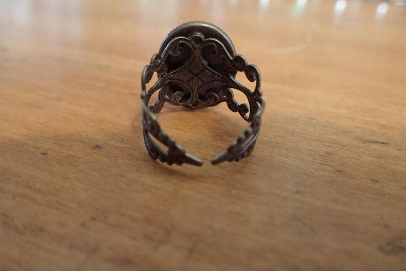 K&ouml;nnte beinhalten: Ein silberner Ring mit einem verzierten Design. Der Ring ist hinten offen und hat ein filigranes Design.