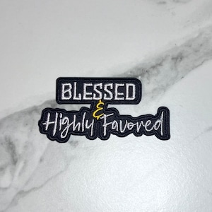 May include: Black and white embroidered patch with the text "Blessed & Highly Favored" in white with an ampersand in gold.